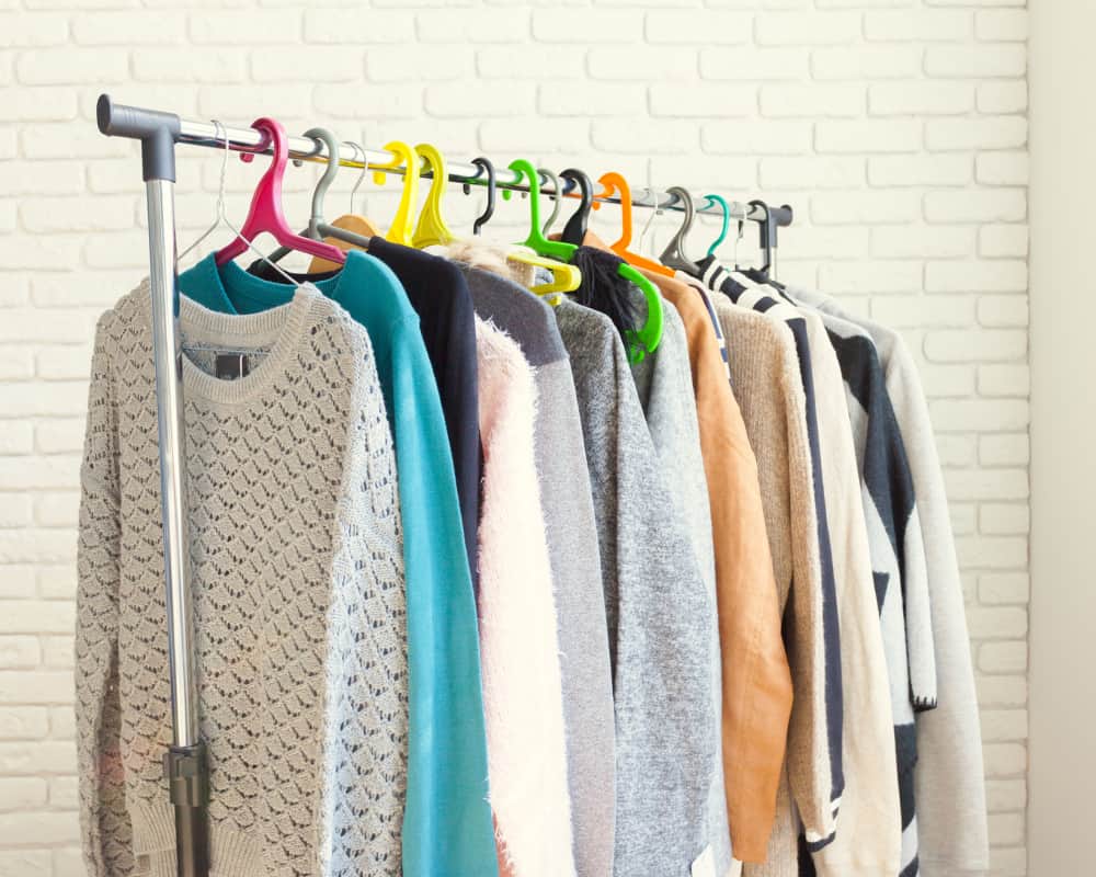 Image of clothing rack with sweaters hanging on it -concept of selling used clothing to make money online.