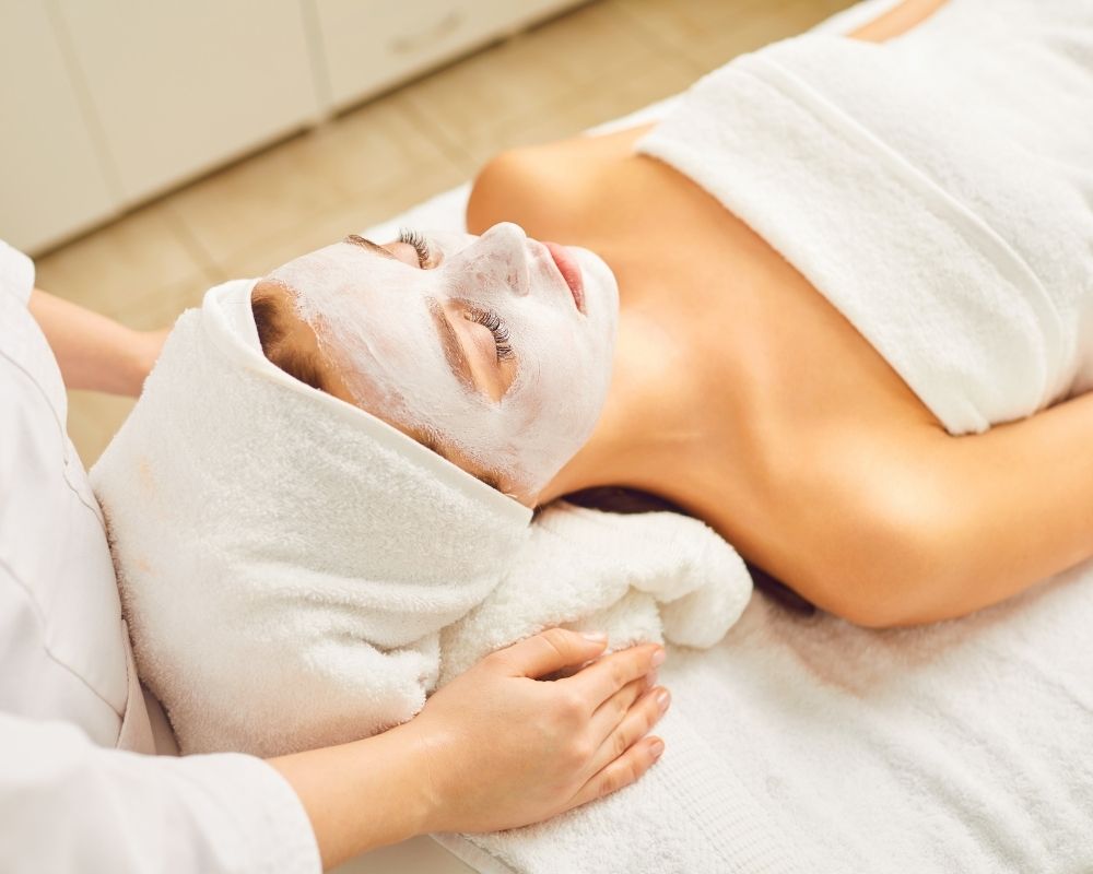 Woman laying down with eyes closed, having a spa day.