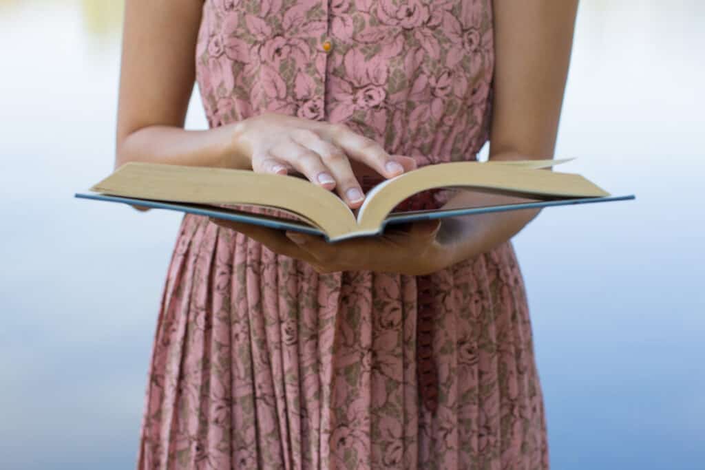 Woman in a pink dress with Bible opened in front of her.