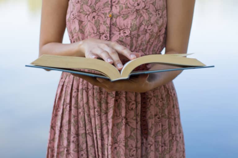 Woman in a pink dress with Bible opened in front of her.