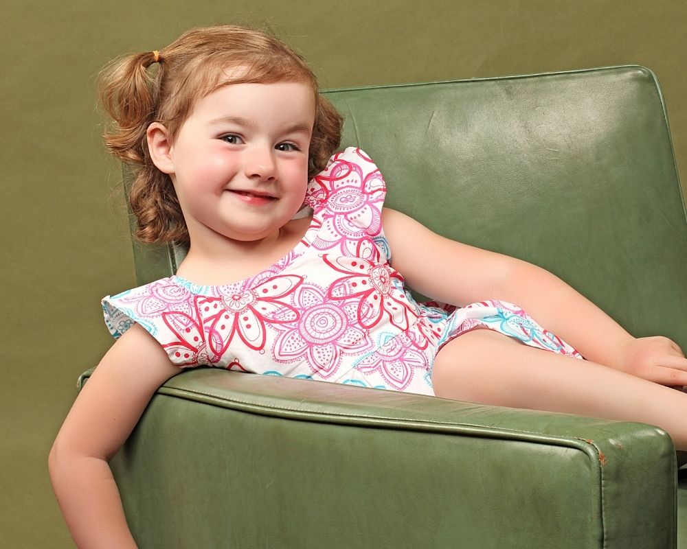 young girl sitting on a sofa with a sly look on her face.