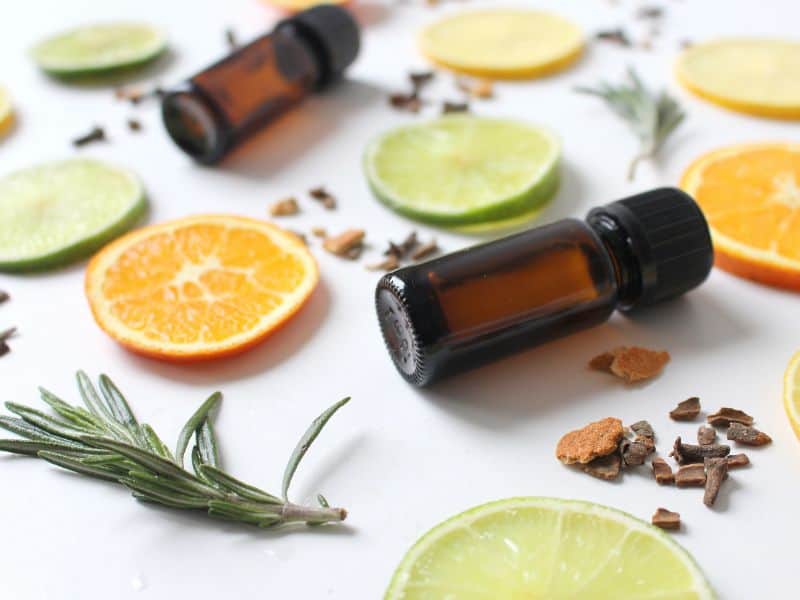 Natural fragrances- slices of lemon, lime, herbs and essential oil bottles on a white background.