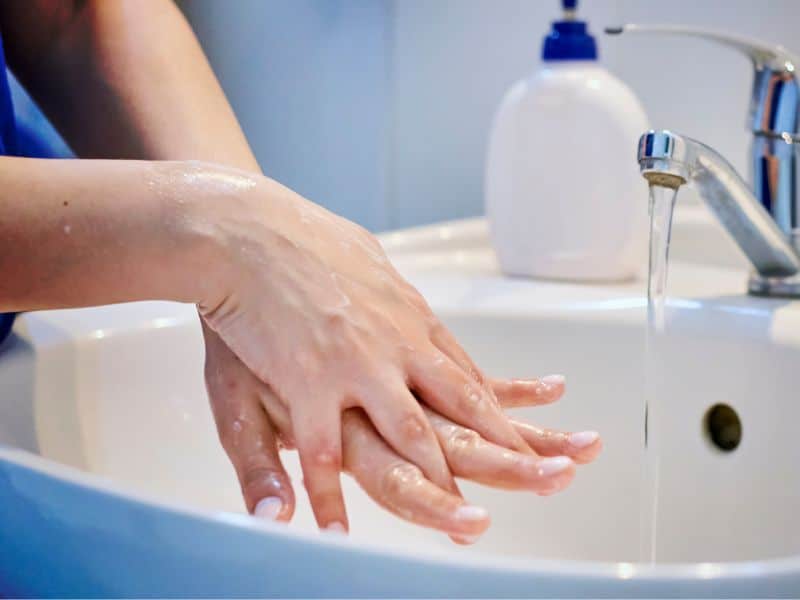 A woman washing her hands under a faucet.