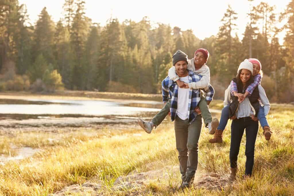 A family of four hiking near a river on a cool autumn day.