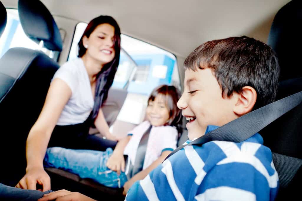 Mom and two sons in the back of the car, paying attention to kids at school pickup.