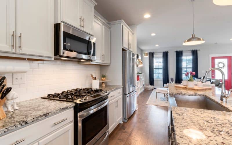 Sparkling clean kitchen with white cabinets and shiny stainless steel appliances.