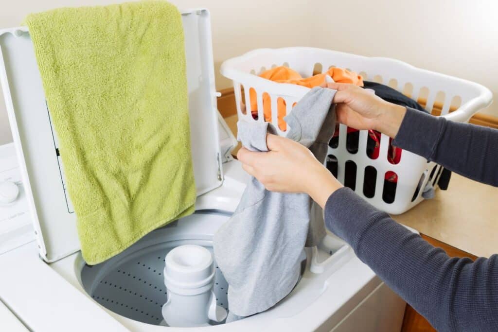 Woman putting laundry into a top loading washing machine.