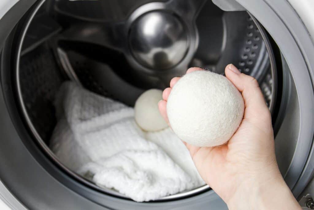 Woman holding a wool dryer ball to place it in a front-loader dryer.