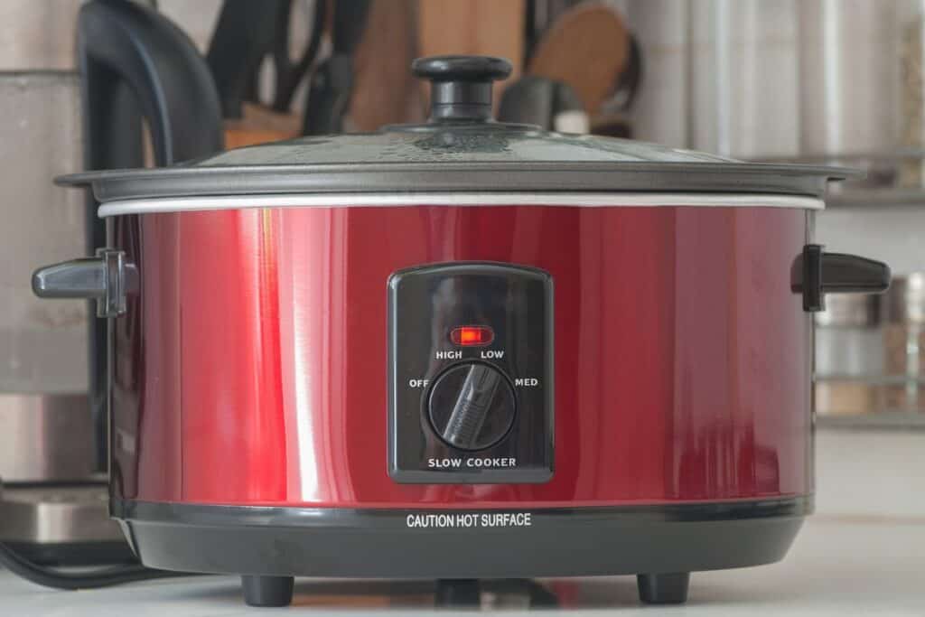 Large red slow cooker on a kitchen counter.