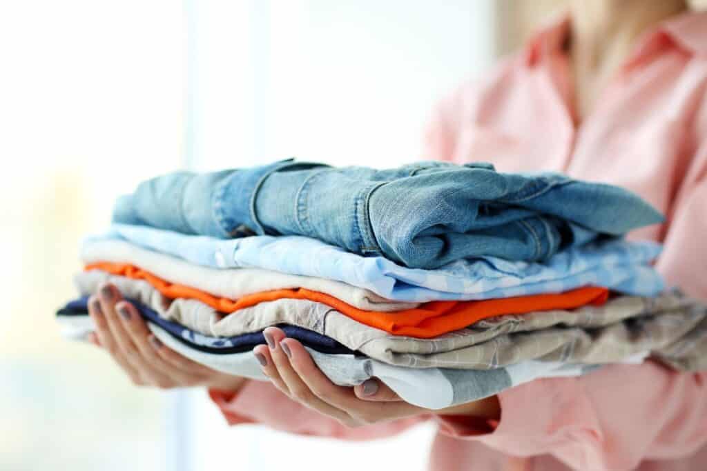 Woman holding a clean stack of clothing.