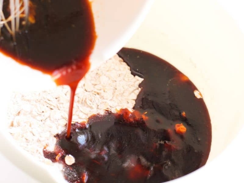 Pouring the dark, rich molasses and other wet ingredients into the dry ingredients.