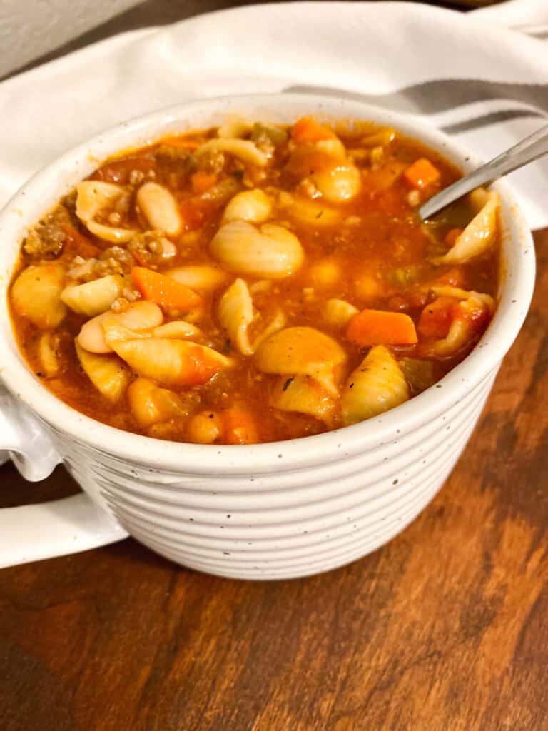 Instant Pot Pasta e. Fagioli- served in a white stoneware mug on a wooden table.