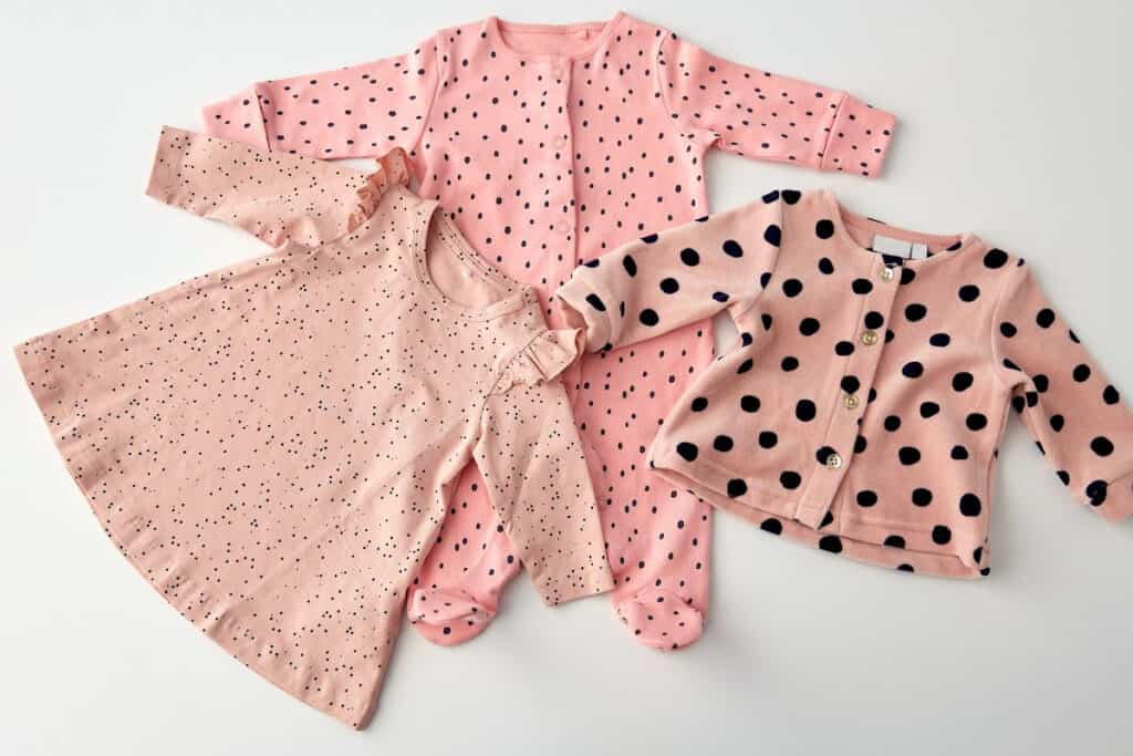 Three pieces of pink baby clothing on a white background.