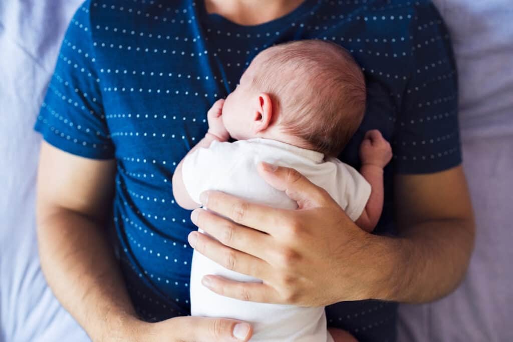 Dad holding sleeping newborn on his chest.