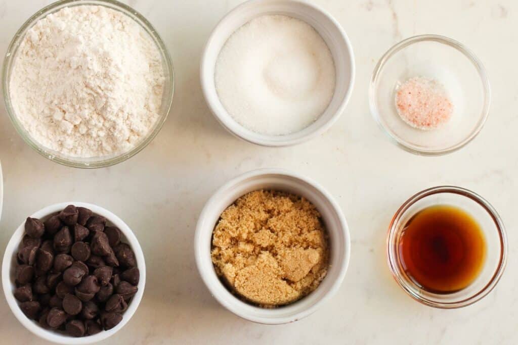 Brownie ingredients in glass dishes on a marble background.