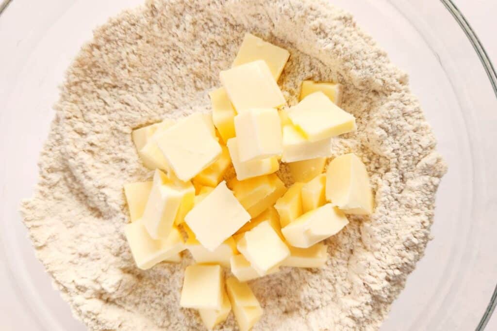 Squares of butter in a bowl of flour mixture, ready to blend with pastry cutter.