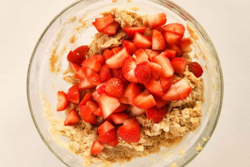 Diced strawberries being mixed into dough mixture.