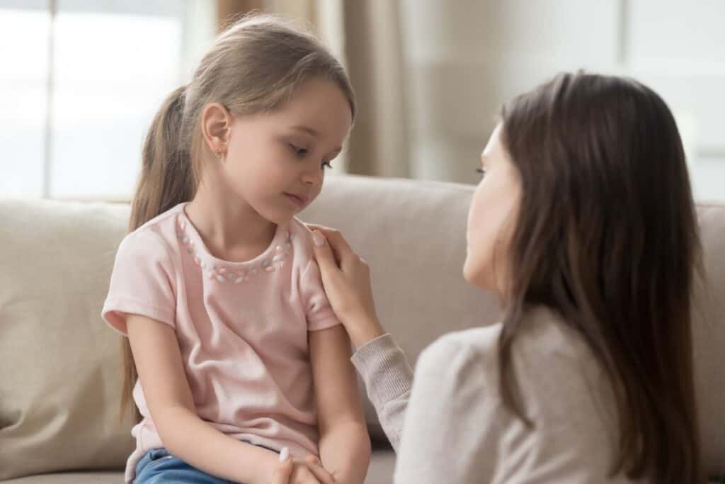 Mom sitting next to little girl, patiently explaining and listening.