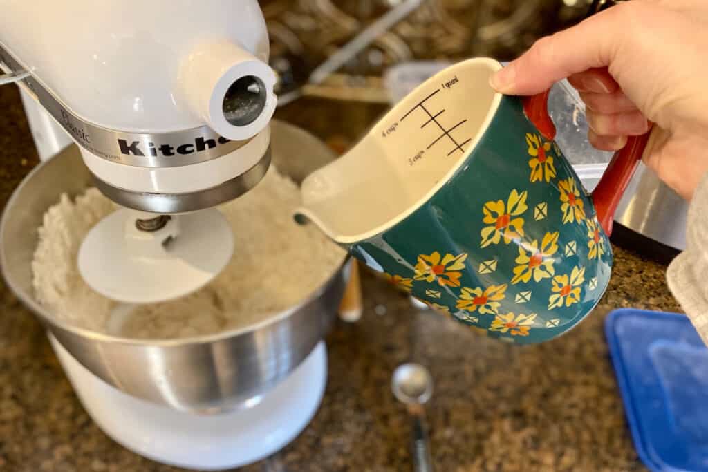 Adding hot water to dry ingredients in stand mixer for crusty french bread recipe.