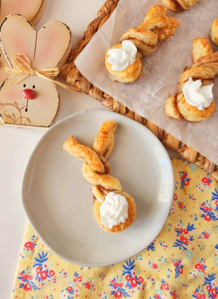 Completed puff pastry twists with whipped cream easter bunny tails on a plate.