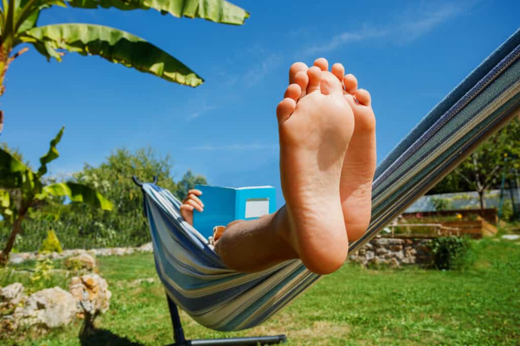 Boy reading a book in a hammock on a summer day.