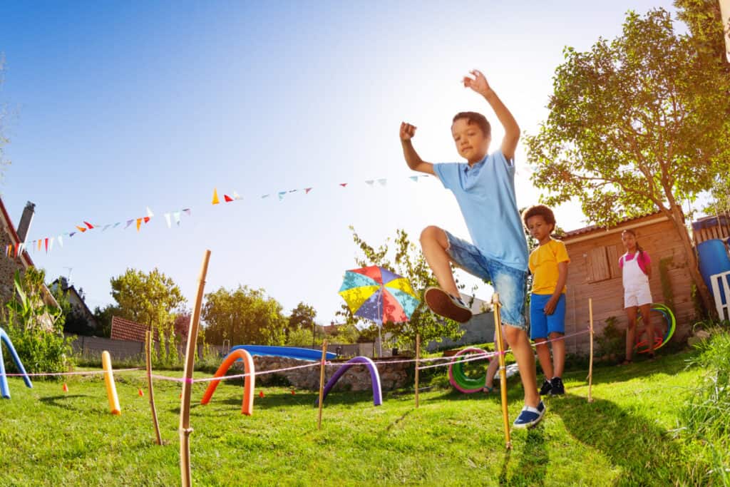 Kids playing in a backyard obstacle course- summer activity idea.