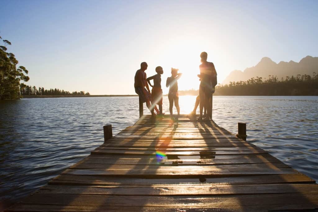 Family resting at the end of the dock at the lake.