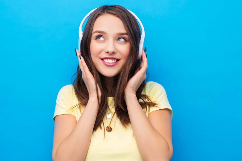 Woman with headphones standing against a blue background.