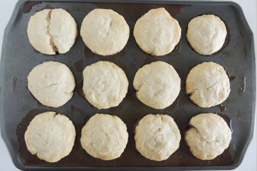 Baked biscuits on top of caramel apple sauce in muffin tins.