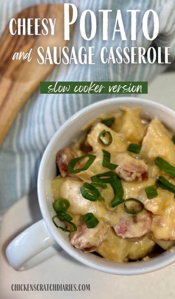 Vertical image of cheesy potatoes and sausage with blue tea towel and wooden spoon in background.