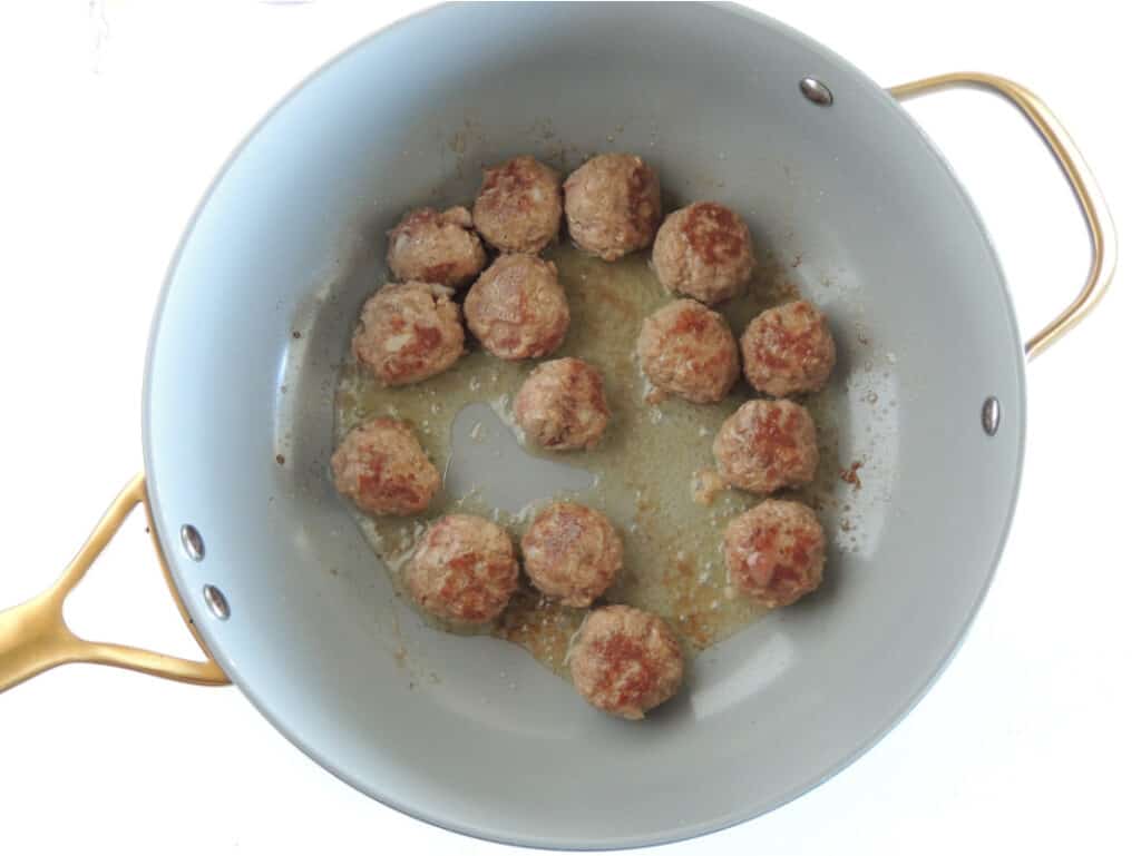 Browning meatballs in avocado oil in a skillet.