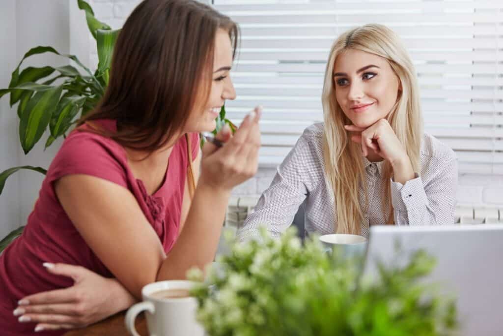 friends confiding over coffee, talking and smiling.