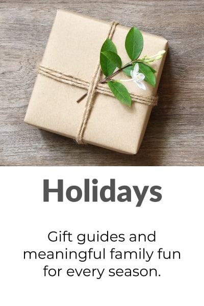 Small gift wrapped in brown paper with fresh greenery and twine, with text "Holidays - Gift guides and meaningful family fun for every season"- links to Holidays category