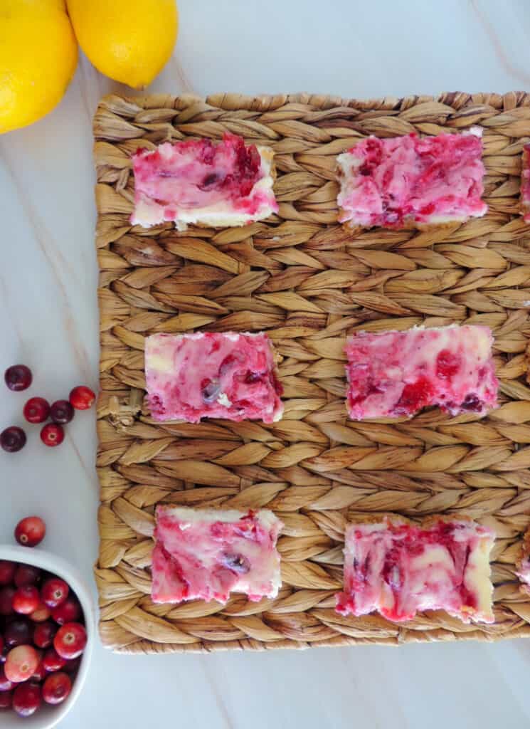 Cheesecake bars cut and placed on a woven mat on a marble counter top.
