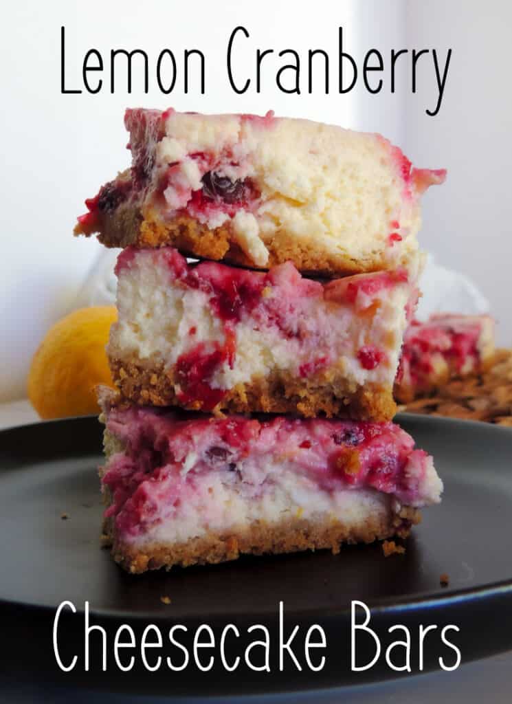 Closeup of a stack of 3 lemon cranberry cheesecake bars on a dark plate.