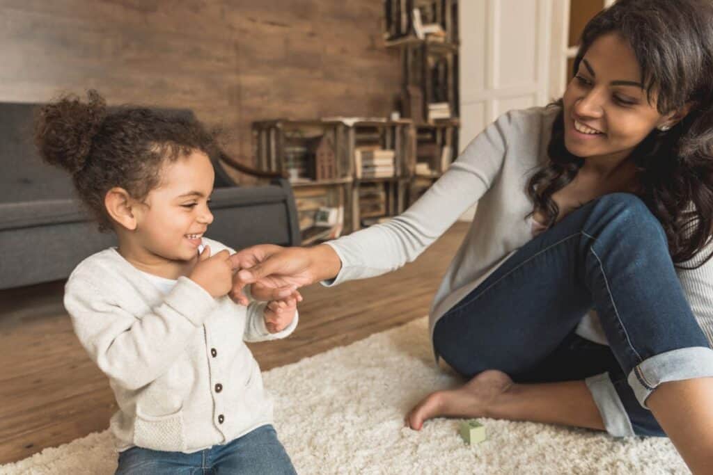 African American mom and preschool daughter playing in the floor together.