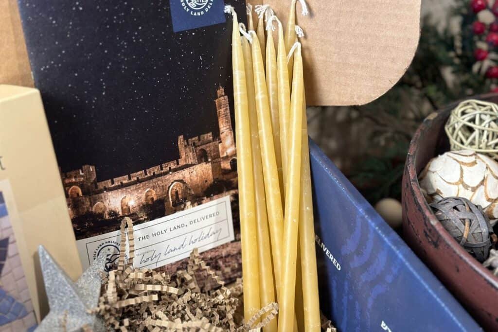 Skinny beeswax candles stacked inside open Artza box.