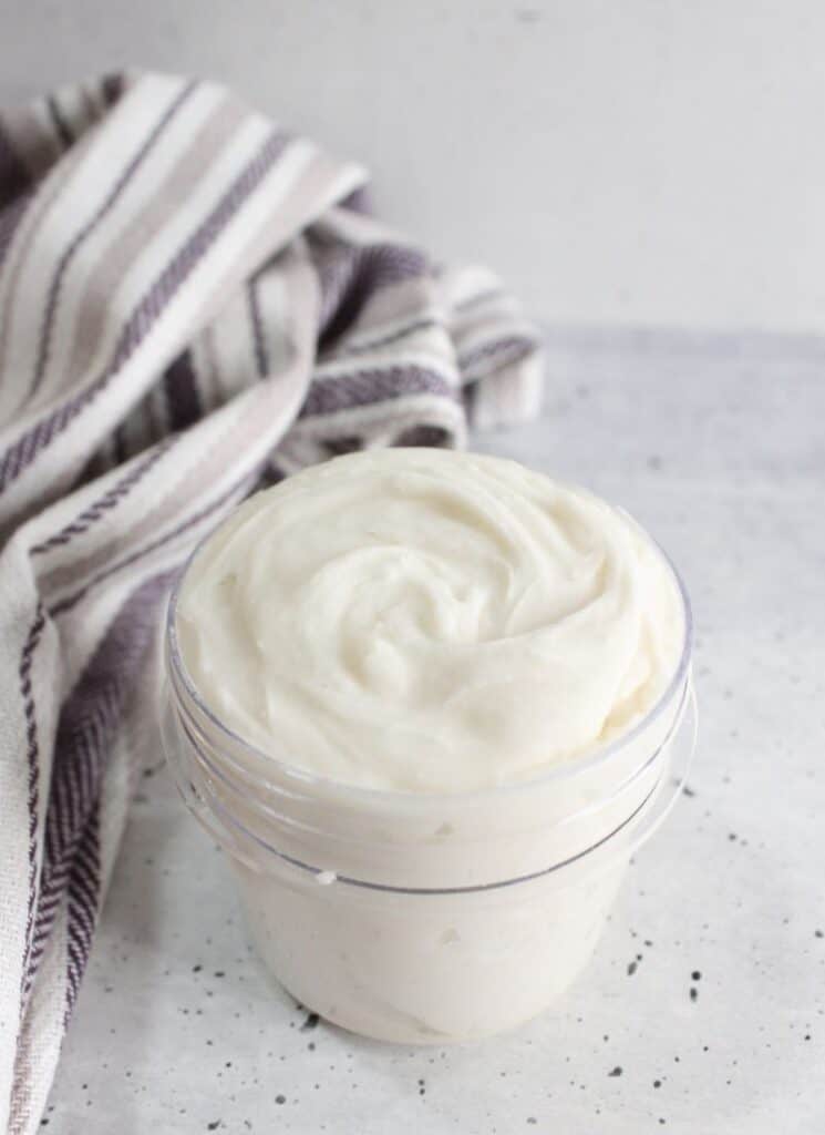 Vertical image of white grout cleaner in a small glass jar.