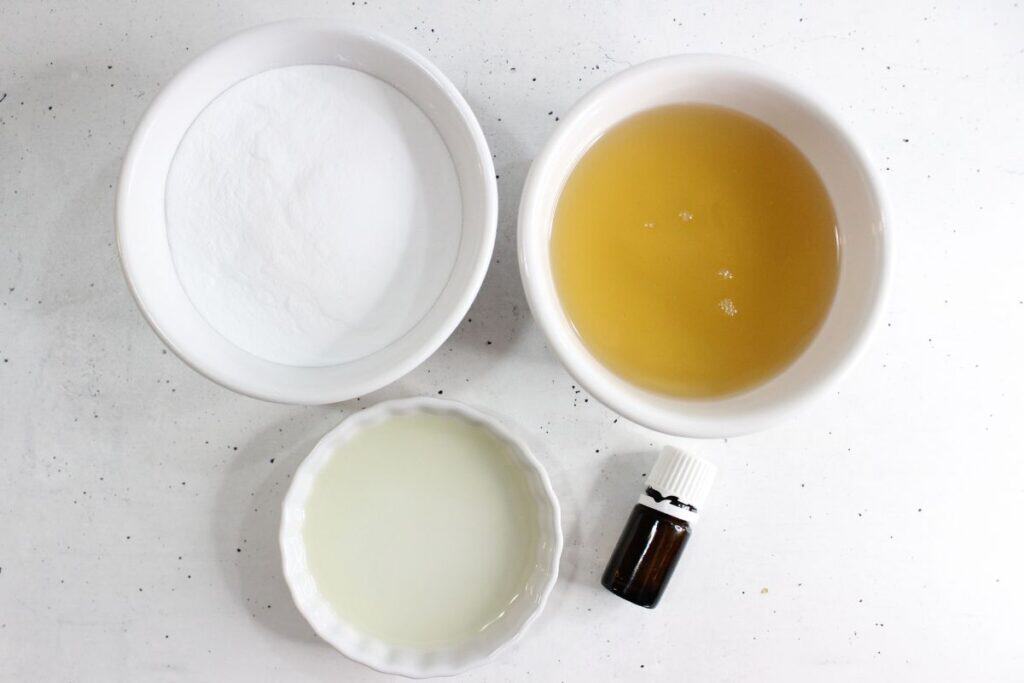 Grout and tile cleaner recipe ingredients on a speckled countertop in ceramic containers.