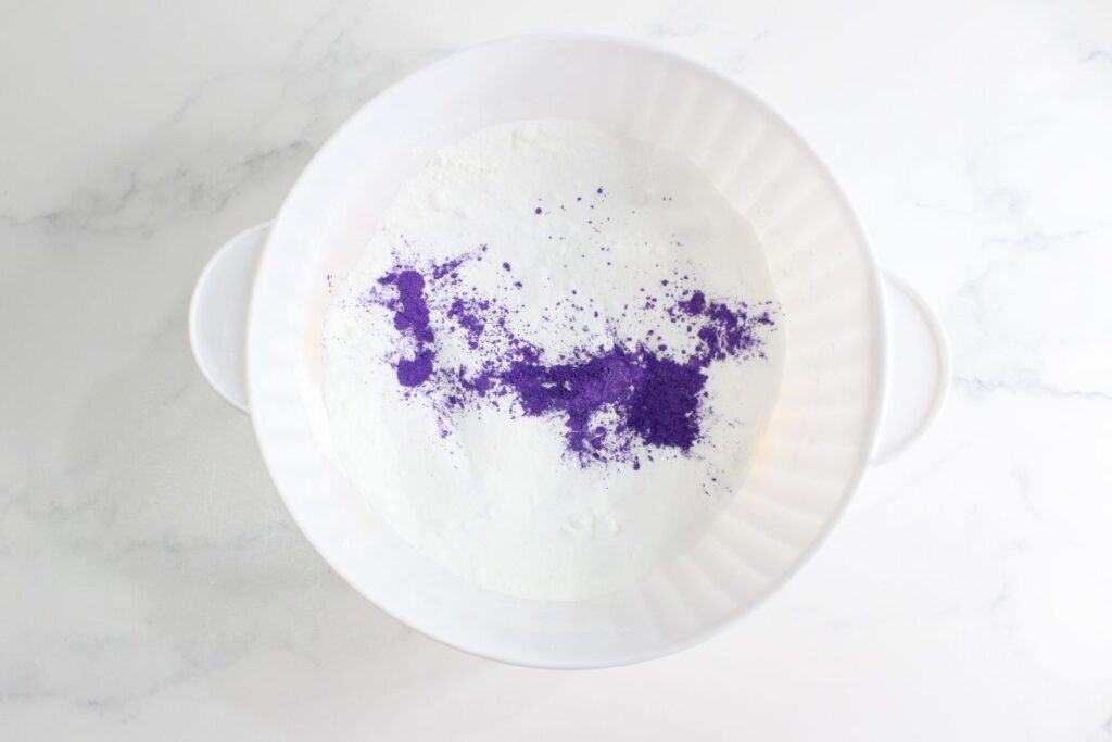Dry ingredients with purple mica powder in a plastic mixing bowl.