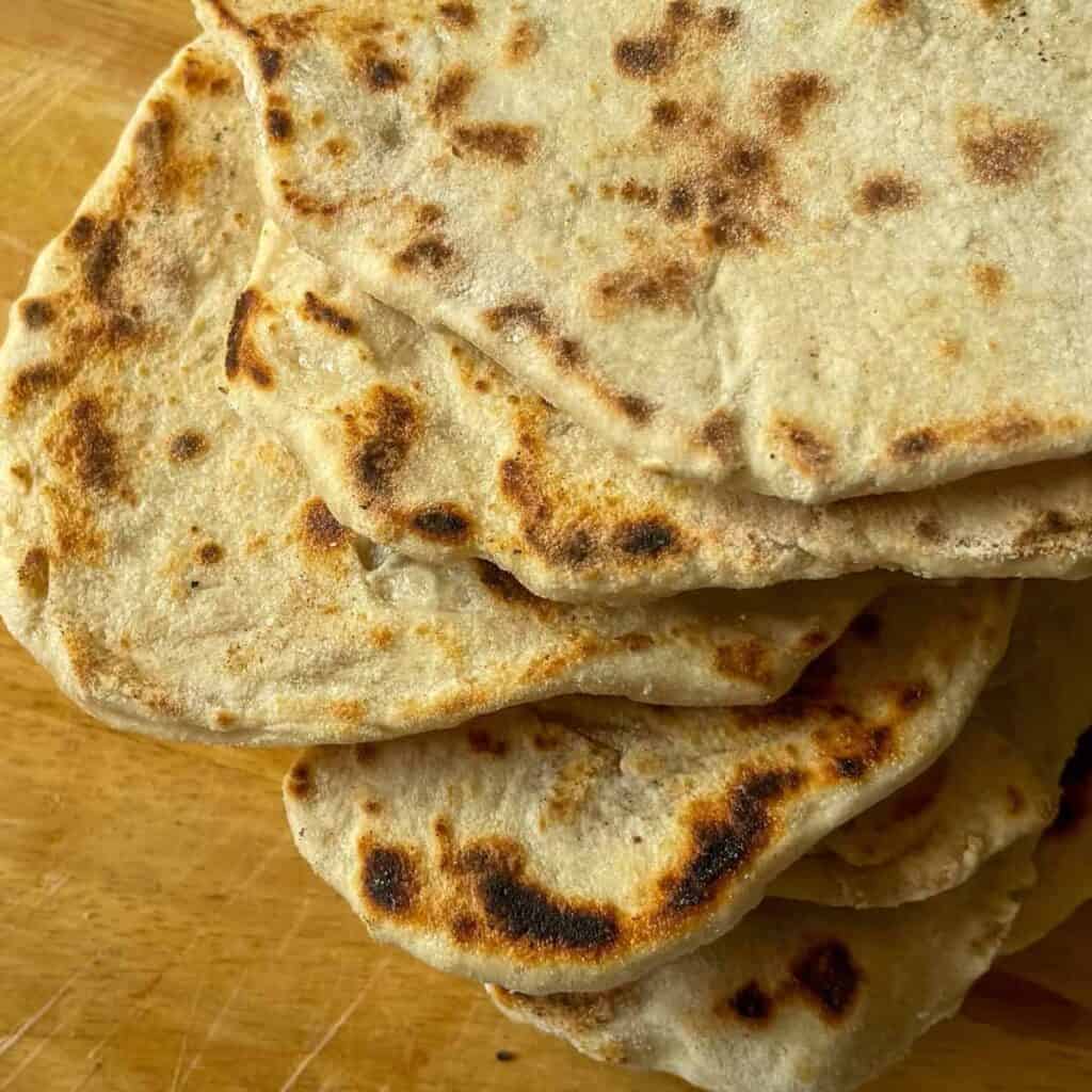 Stack of flatbreads on a wooden cutting board.