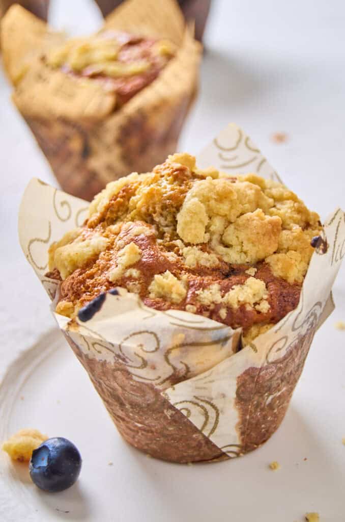 Streusel topped blueberry muffins in a tulip muffin liner.