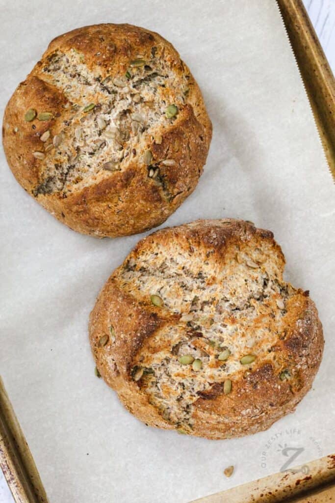 Two loaves of soda bread topped with seeds.