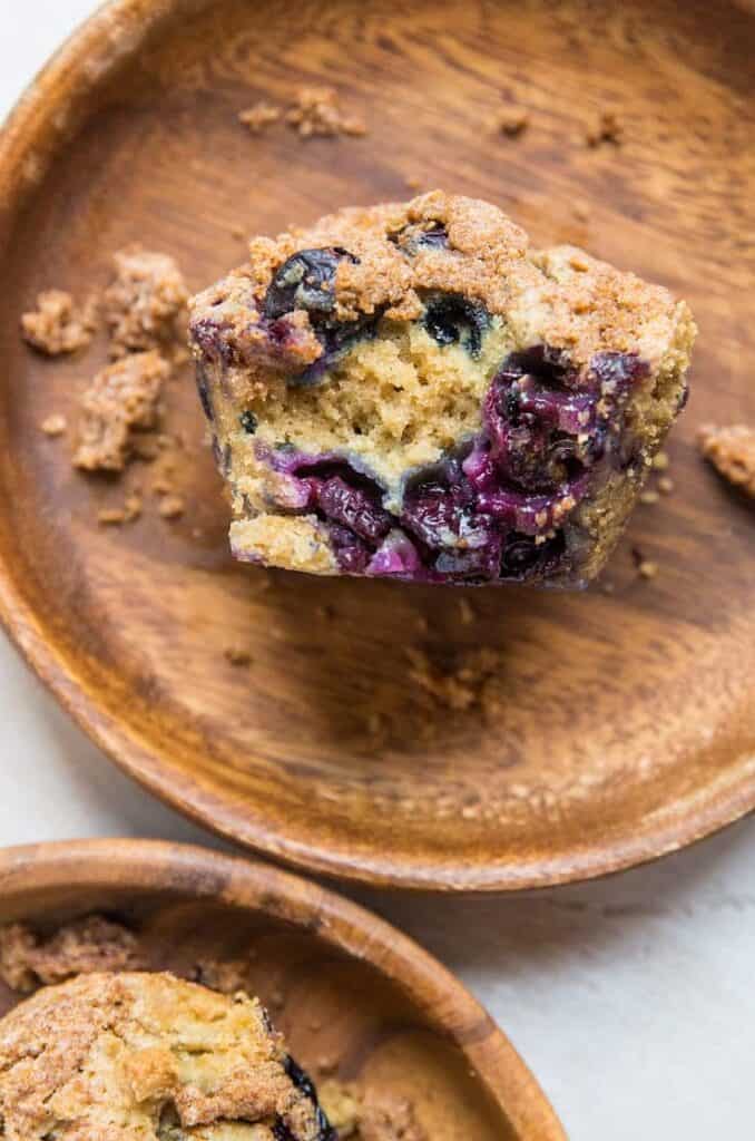 Blueberry muffin cut in half on a wooden plate.