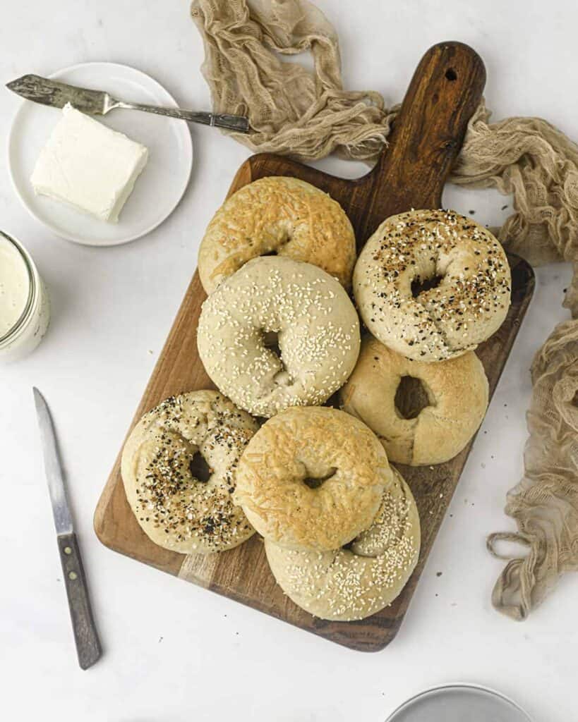 Sourdough bagels on cutting board with various toppings.