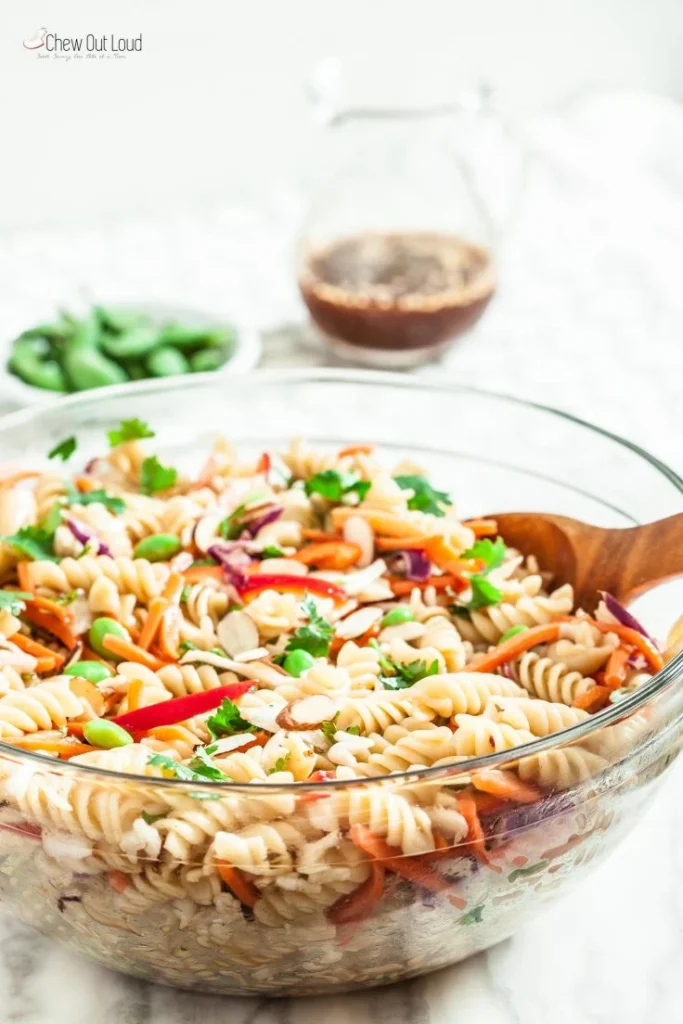 Asian pasta salad in a clear mixing bowl.