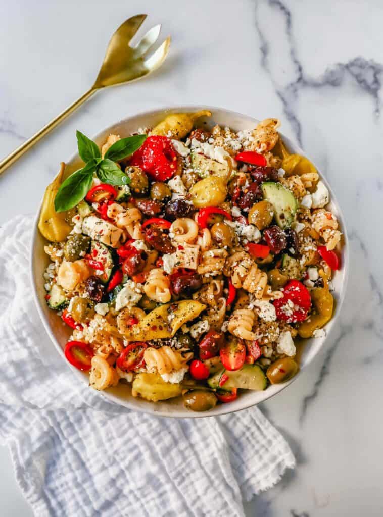 Greek pasta salad with pepperoncini's and feta cheese in a large ceramic bowl.