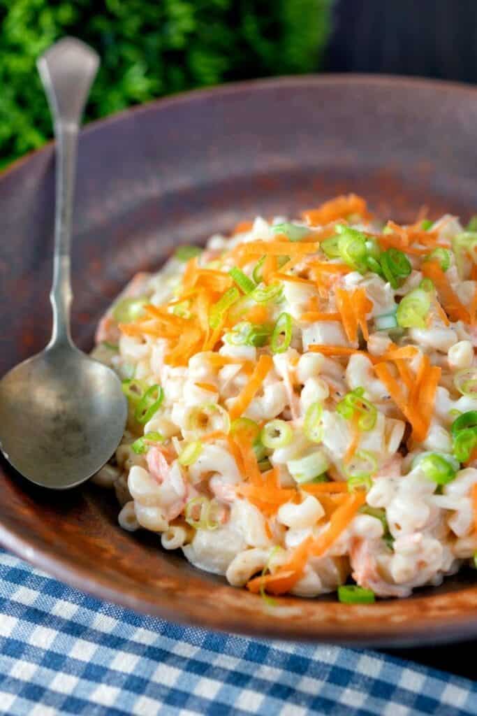 Hawaiian macaroni pasta salad in a dark colored bowl with spoon.