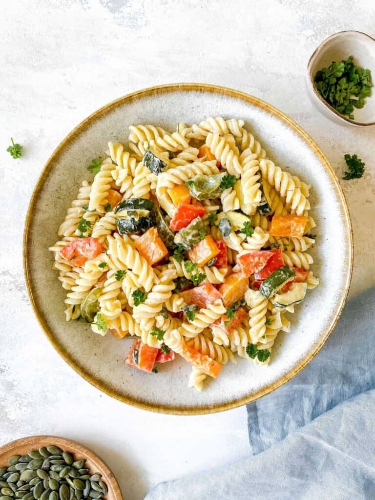 Fresh rotini pasta salad topped with roasted vegetables.