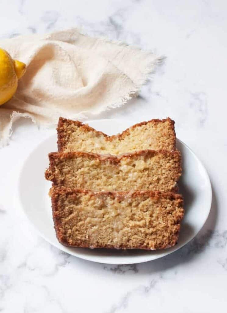 Three slices of glazed sourdough lemon cake on a plate.